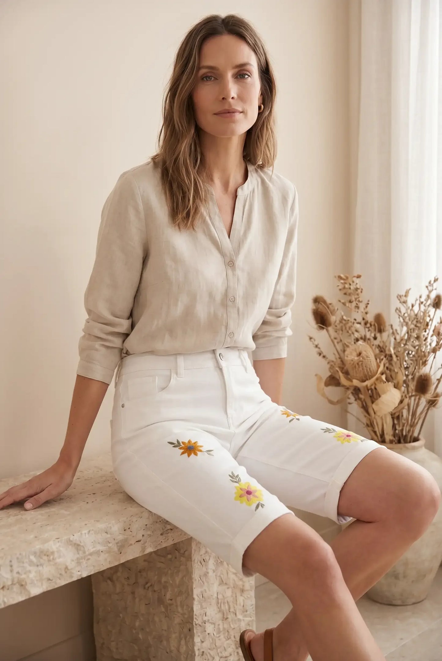 Mujer con shorts blancos bordados con flores y blusa casual de lino, look verano cómodo y estiloso