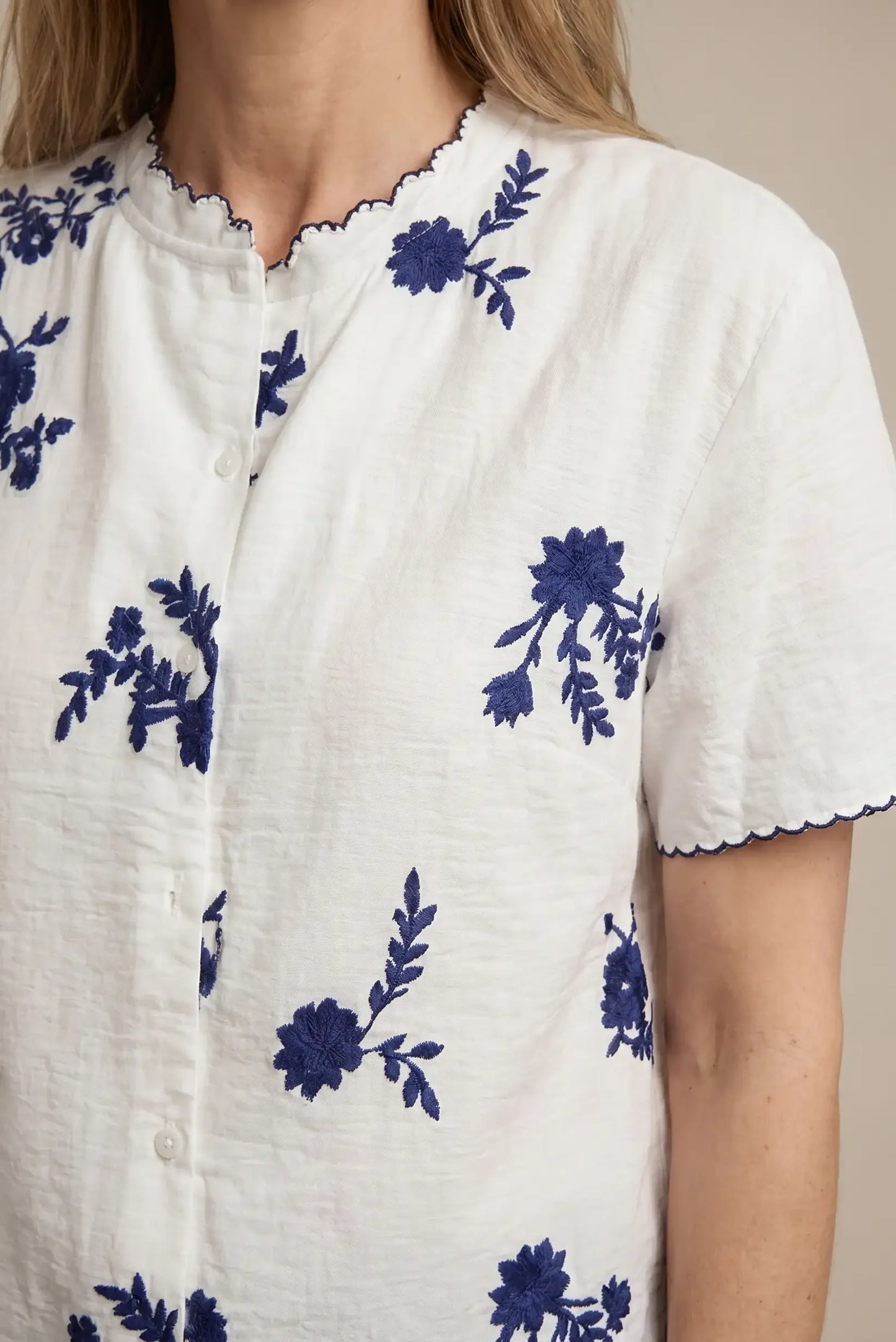 Camisa blanca de mujer con bordado floral azul y manga corta, detalle casual elegante