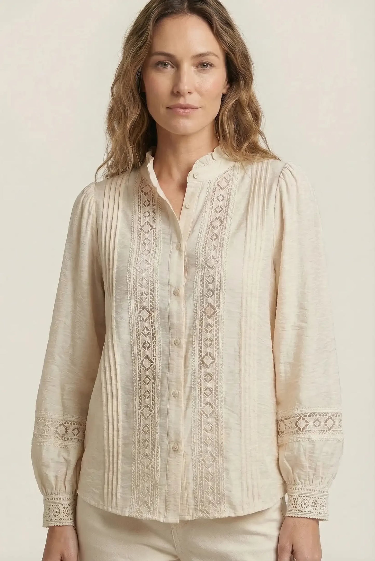 Mujer con camisa beige de manga larga, bordados y encaje, estilo casual primaveral