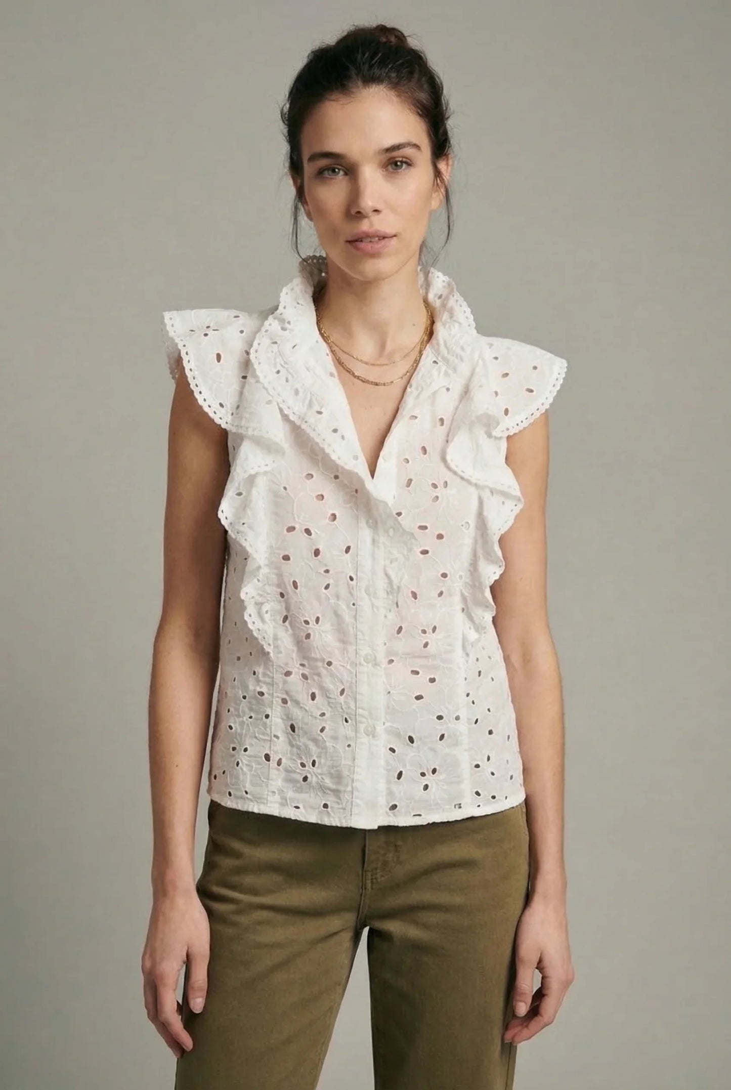 Mujer con blusa blanca calada de primavera sin mangas y volantes, moda femenina casual.