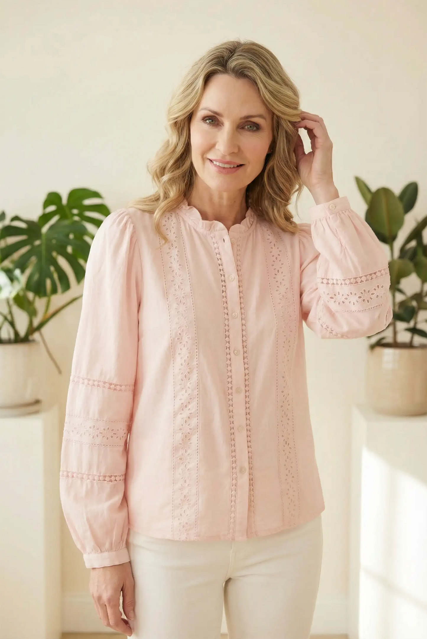 Mujer con camisa rosa pastel bordada de CHICA del Sur, moda femenina casual, fondo con plantas.