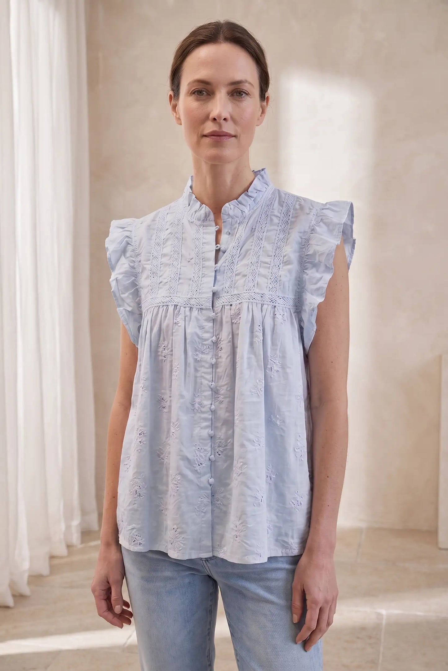 Mujer con camisa sin mangas azul pastel y detalles bordados, estilo casual de verano