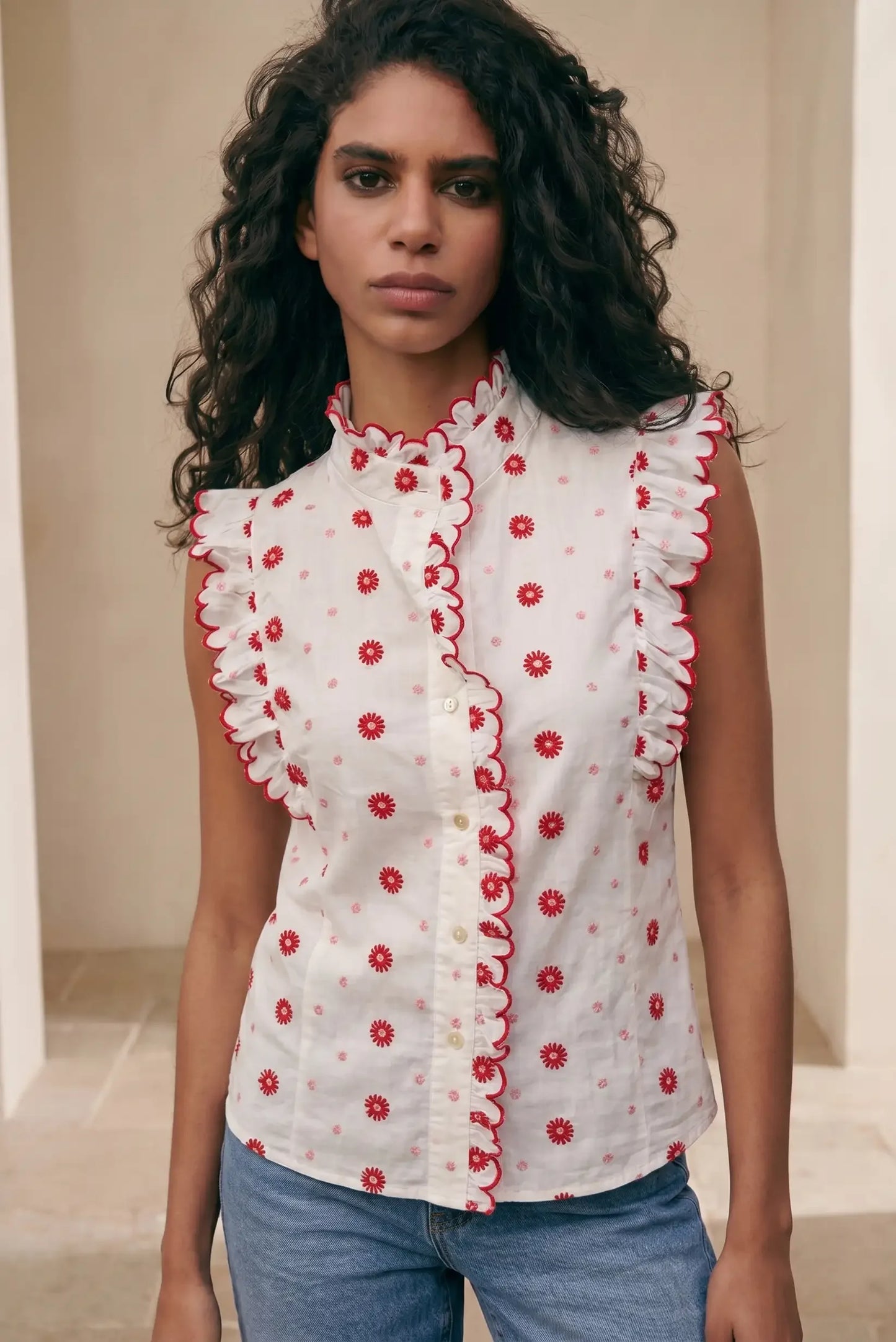 Camisa sin mangas blanca para mujer con bordados florales rojos y volantes, estilo casual.