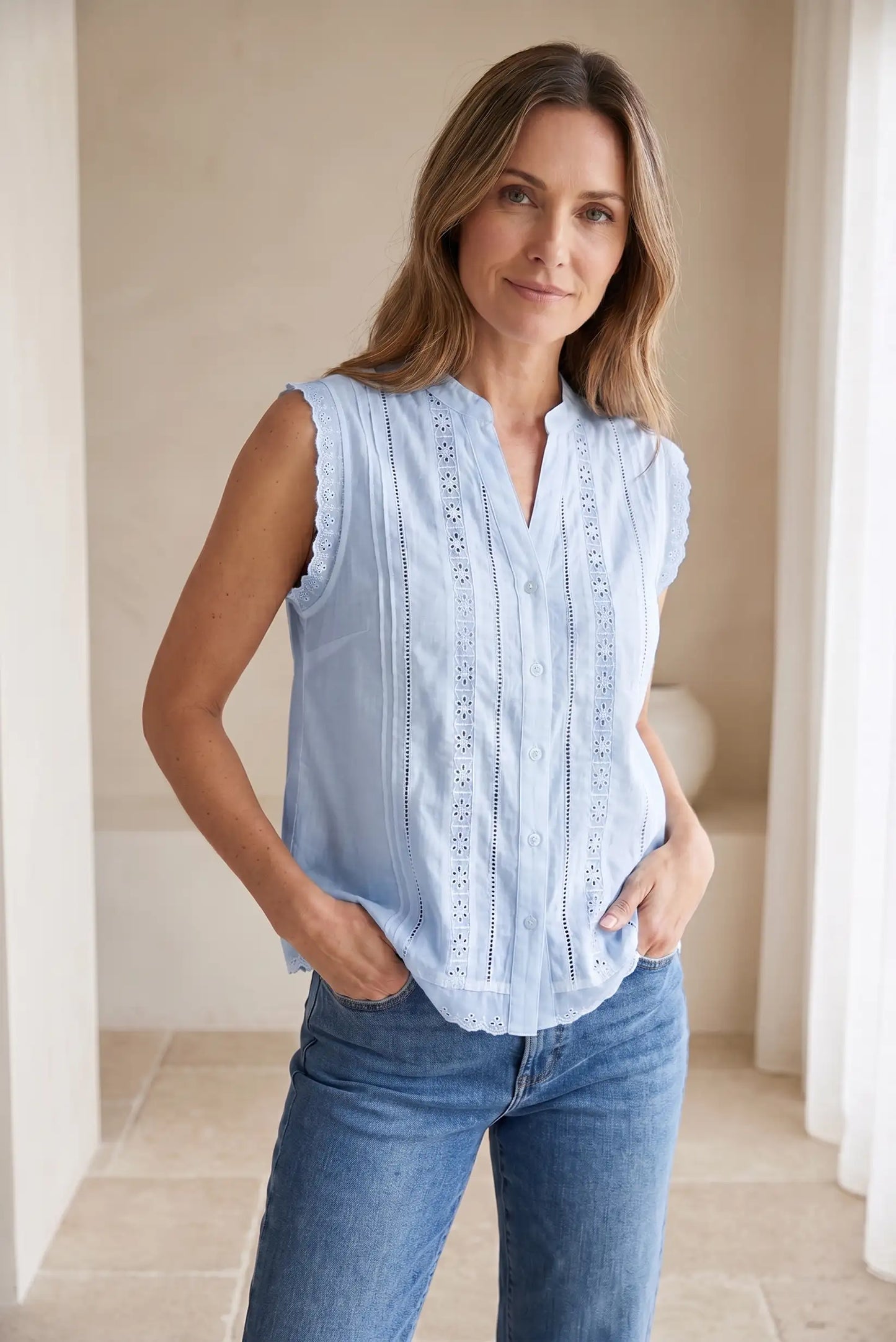 Mujer con camisa sin mangas celeste de verano y jeans, estilo casual femenino