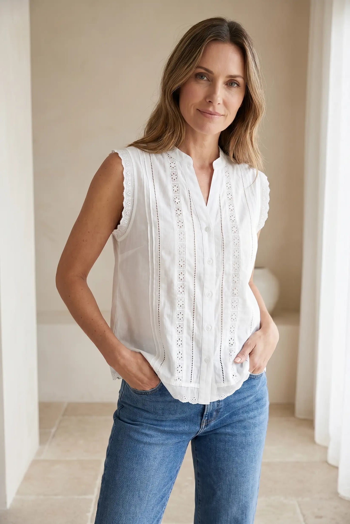 Mujer con camisa sin mangas blanca de algodón y encaje, combinada con jeans azul claro.