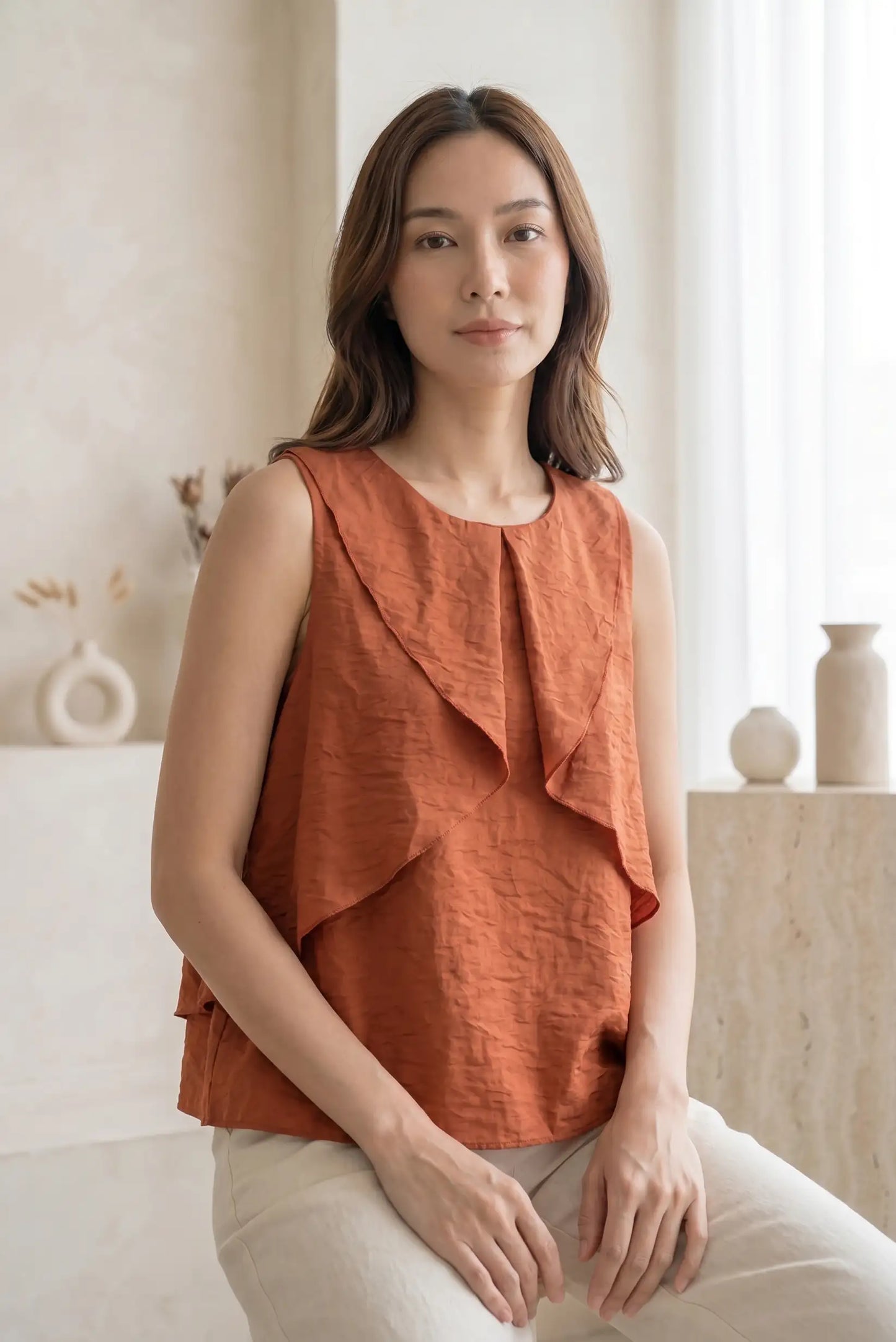 Mujer con blusa sin mangas teja, volantes, look casual de primavera, fondo minimalista