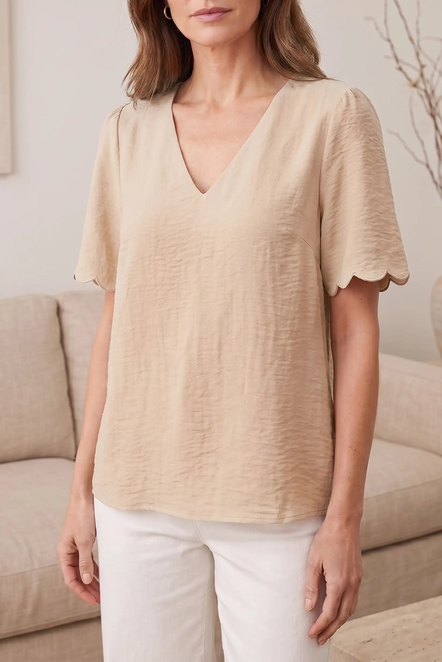 Blusa beige con cuello en V y mangas cortas con detalle de volante, ideal para looks casuales y estilosos.