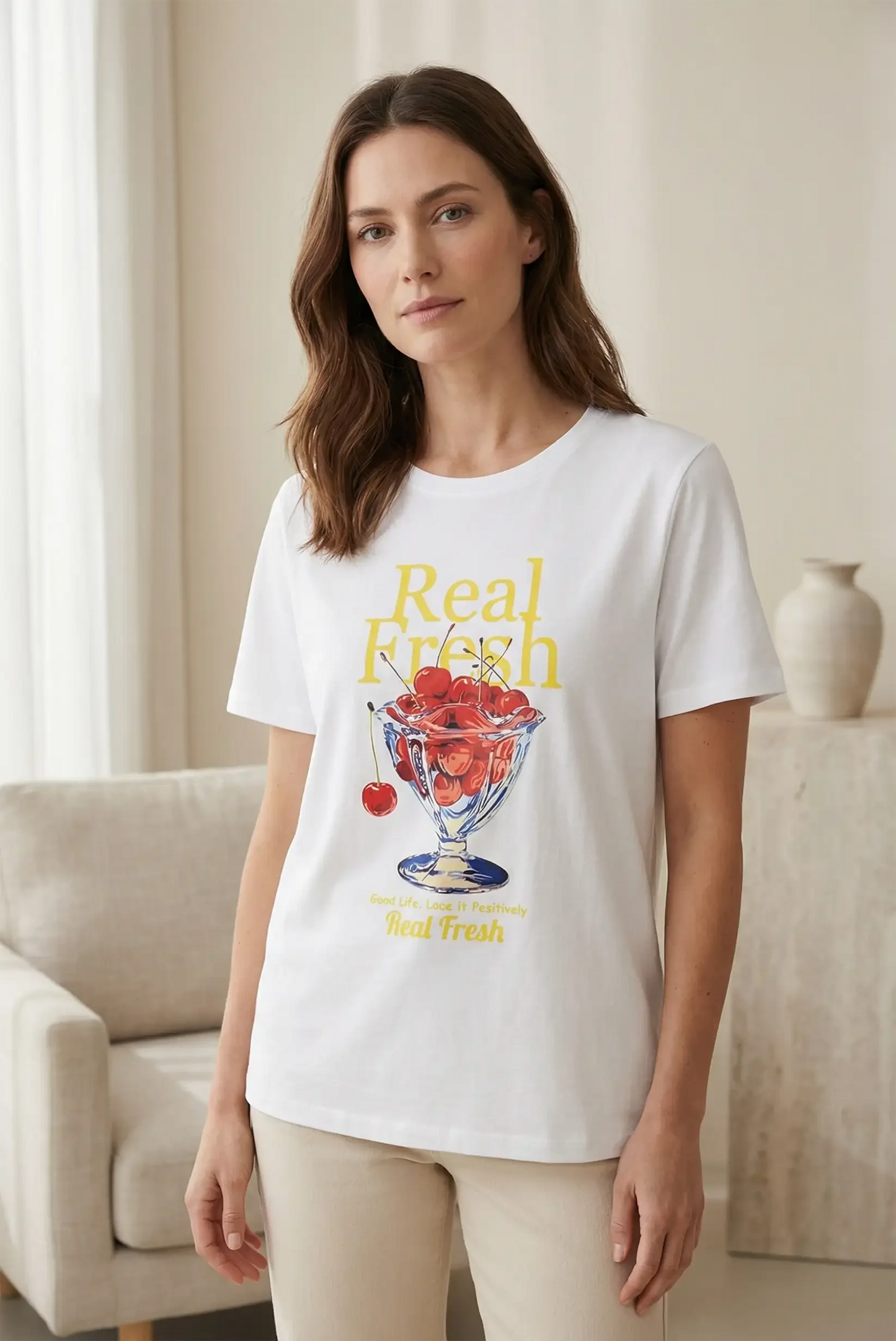 Mujer con camiseta blanca de manga corta con diseño de cerezas y mensaje 'Real Fresh', moda casual femenina.