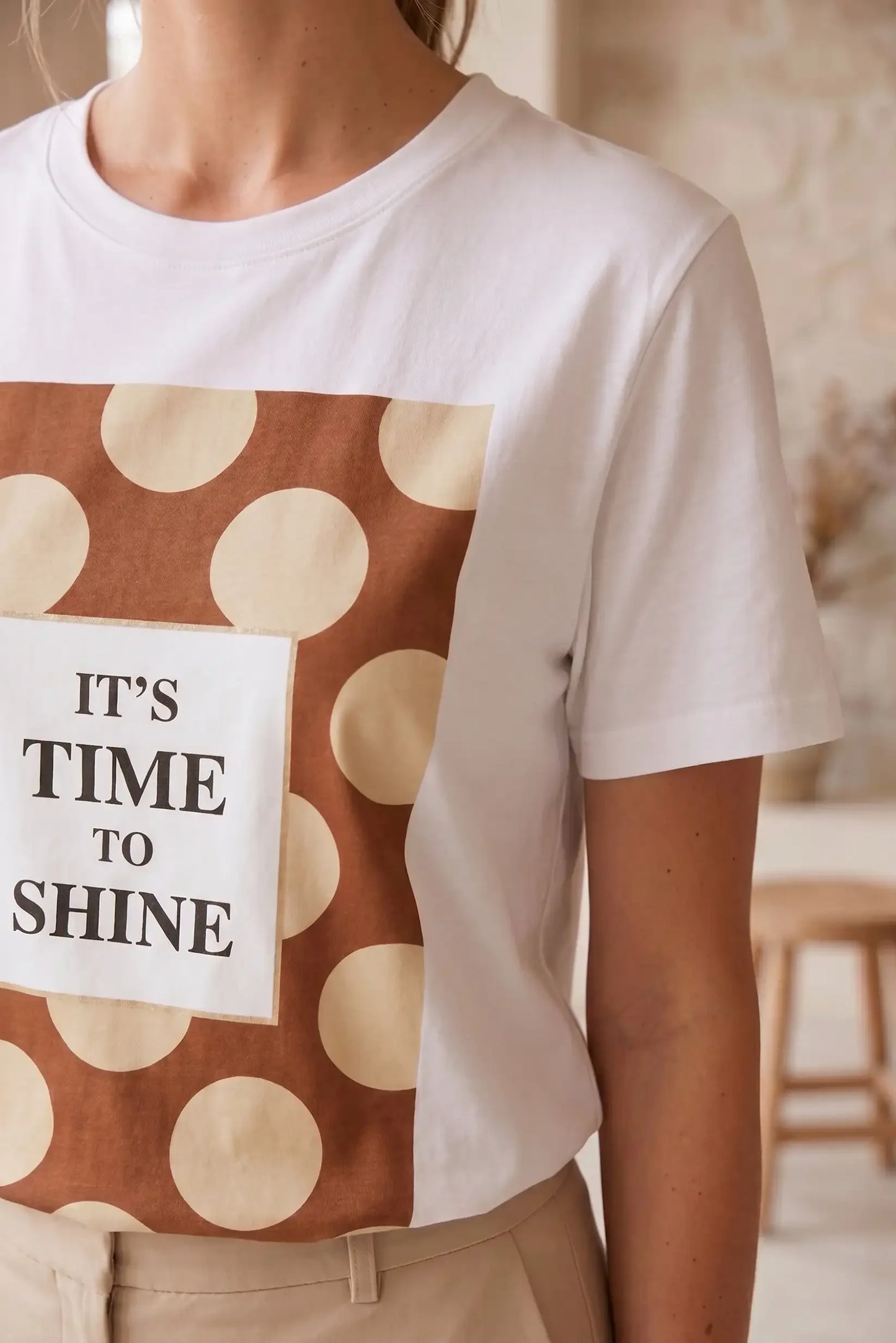 Camiseta mujer blanca de manga corta con estampado de lunares beige y marrón y texto "IT'S TIME TO SHINE".