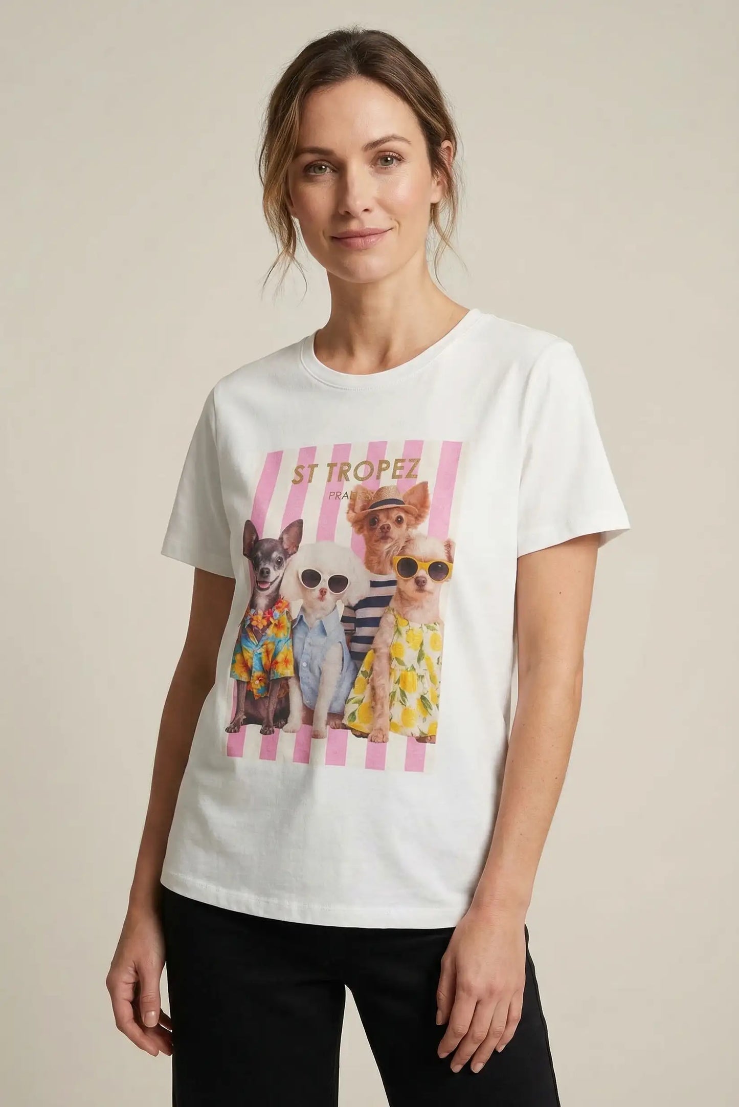 Mujer con camiseta blanca de primavera, estampado de perros con gafas y ropa colorida, fondo beige.