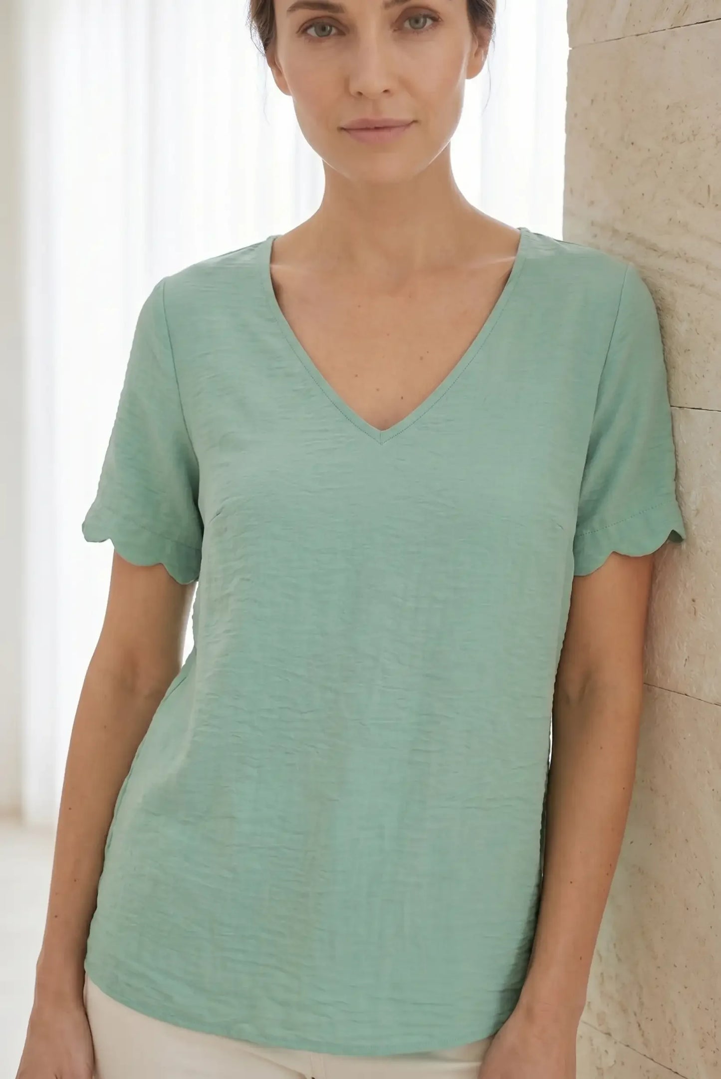 Camiseta verde menta con cuello en V y mangas con volante, ideal para looks casuales y cómodos.