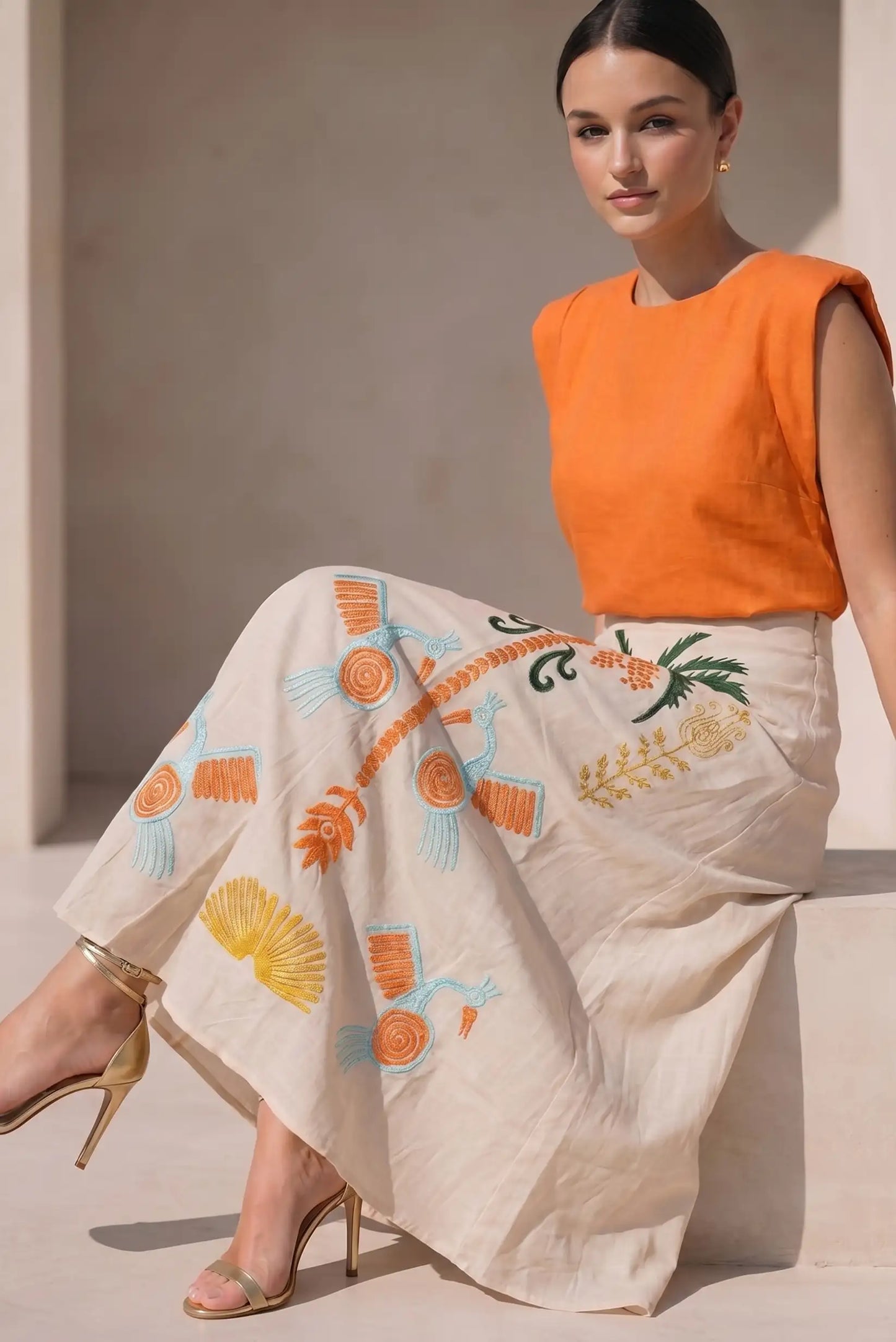 Falda larga beige con bordados tropicales en naranja y verde, top sin mangas naranja.