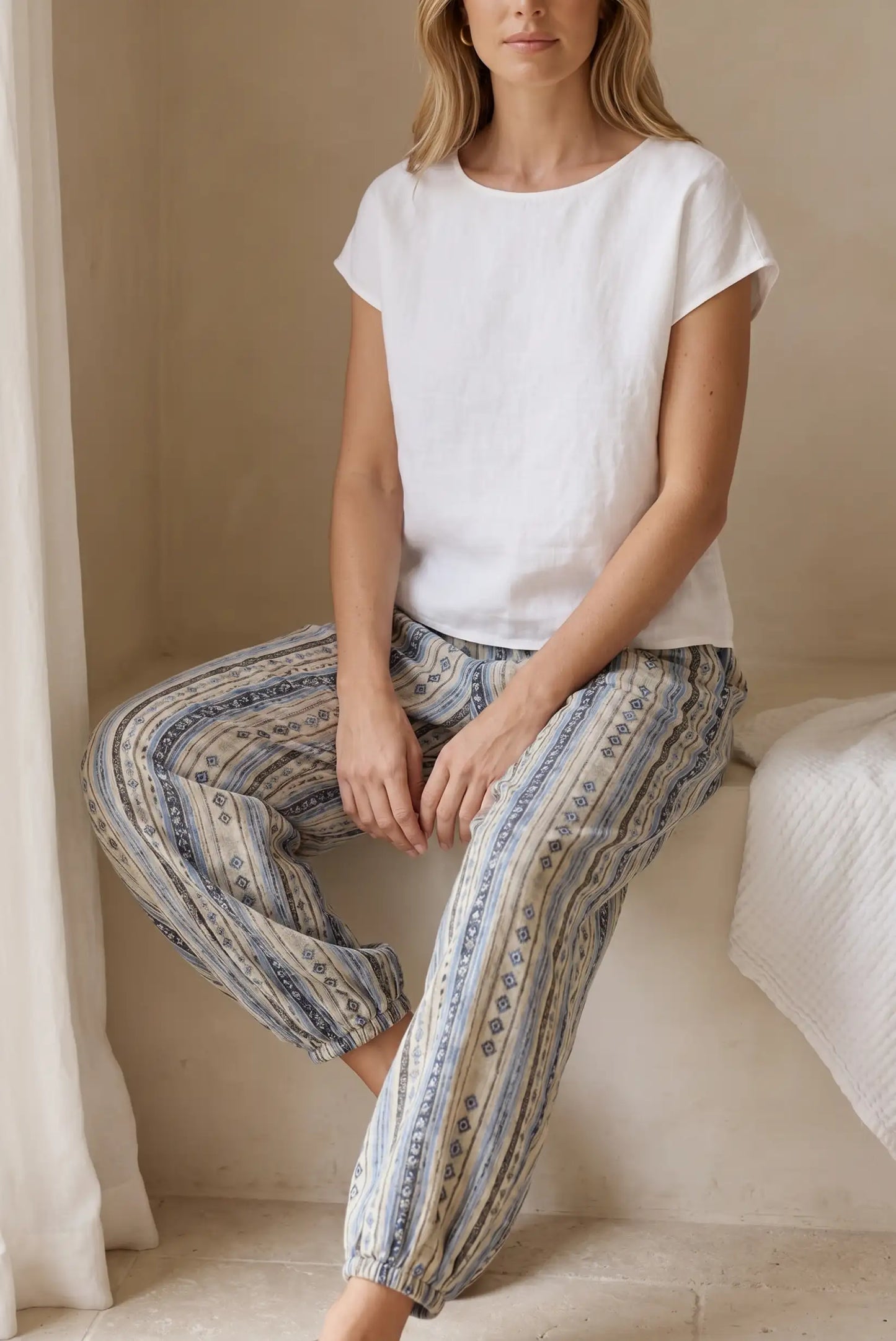 Mujer con pantalón bombacho azul étnico y blusa blanca, moda casual cómoda