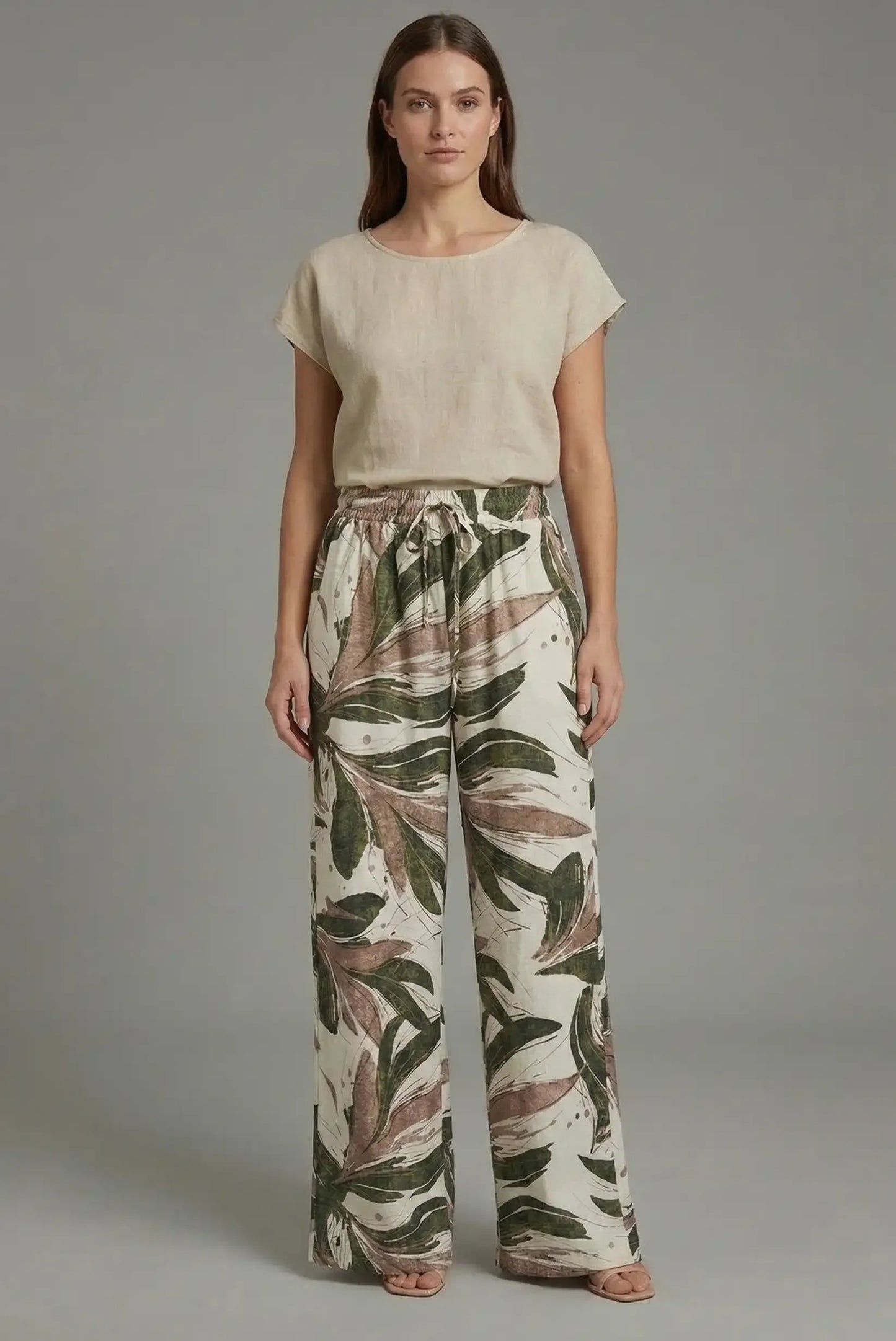 Mujer con pantalón fluido de primavera estampado tropical en verde y marrón, blusa beige.
