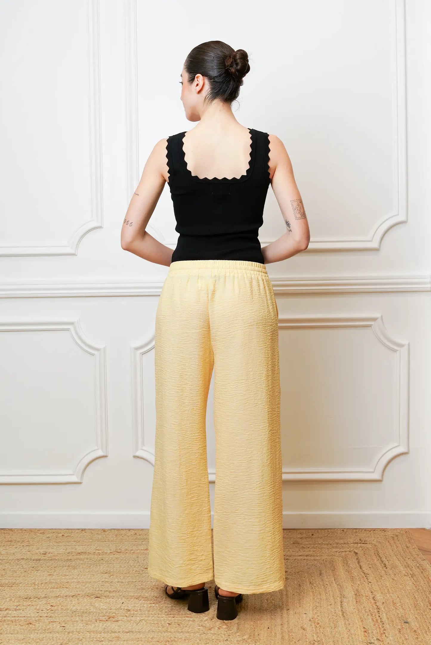 Pantalón largo mujer amarillo pastel primavera, de tiro alto y pierna ancha, visto por detrás.