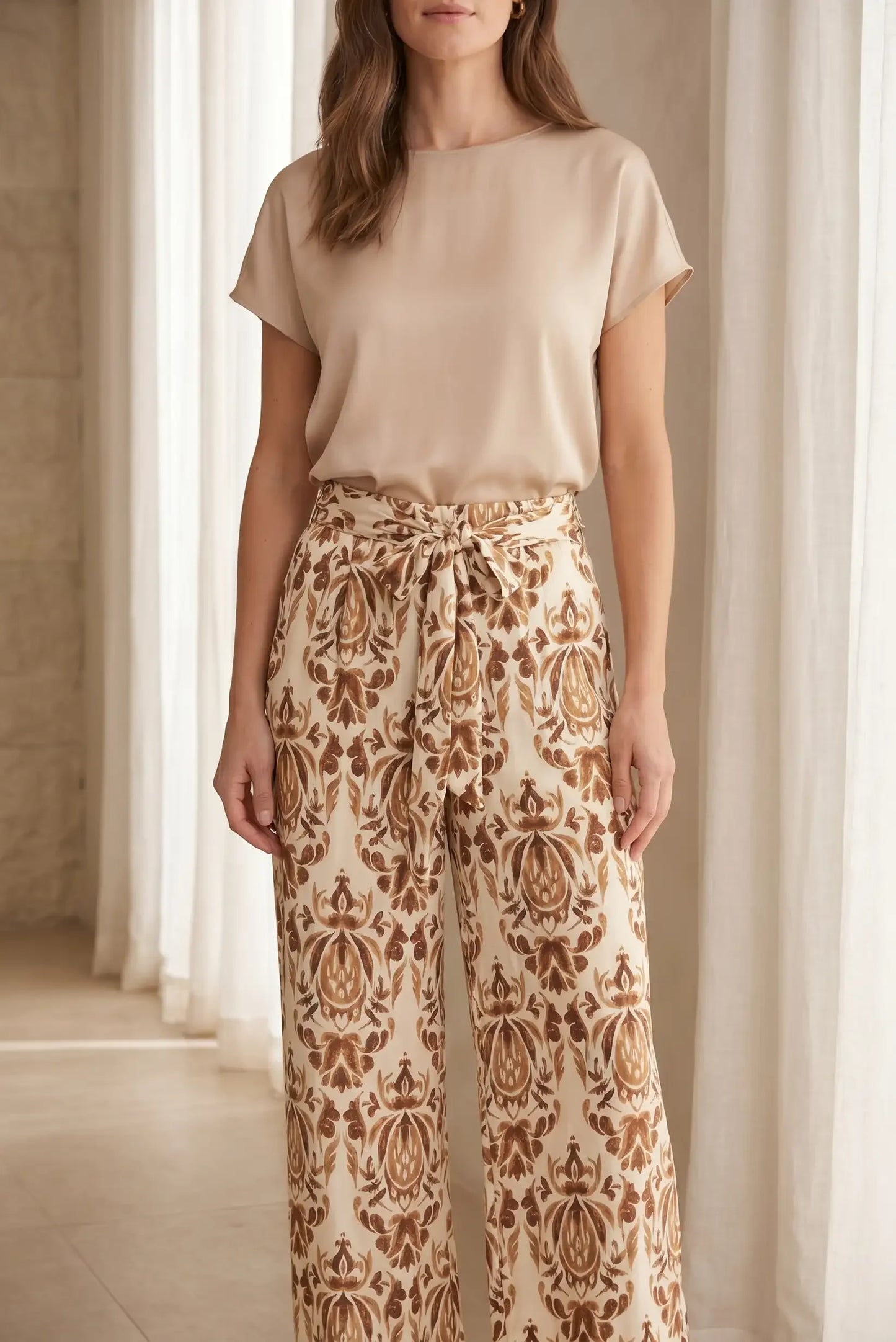 Pantalón largo fluido de mujer con estampado de hojas marrón y blanco, tiro alto y lazo en la cintura.