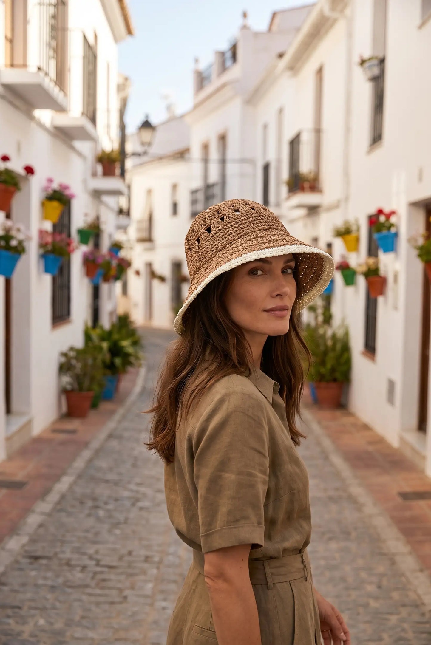 Mujer con sombrero de paja tejido y vestido casual en calle blanca con flores, moda femenina verano