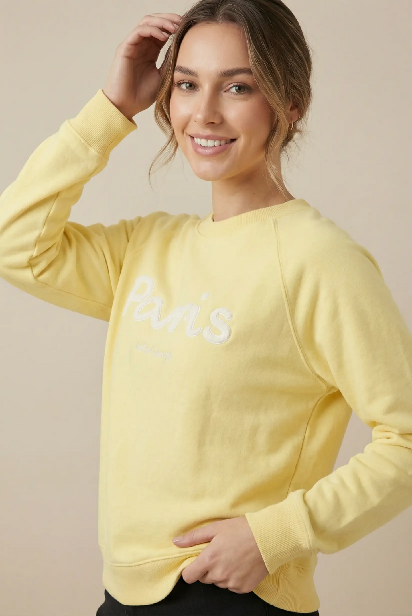 Mujer sonriente con sudadera amarilla pastel con texto 'Paris', moda casual CHICA del Sur