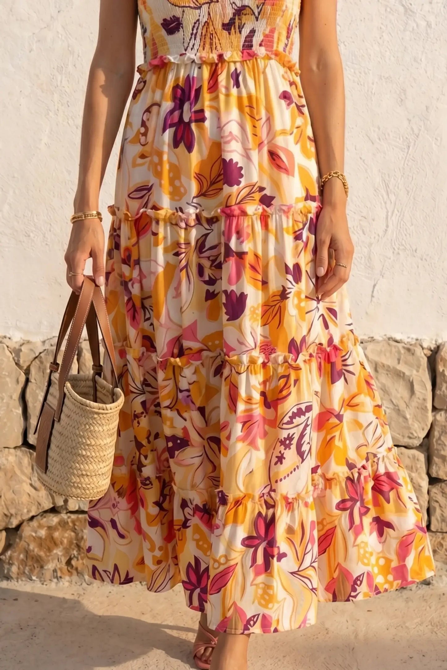 Vestido largo floral con volantes en tonos amarillos y rosas, ideal para verano. Bolso de paja y sandalias.