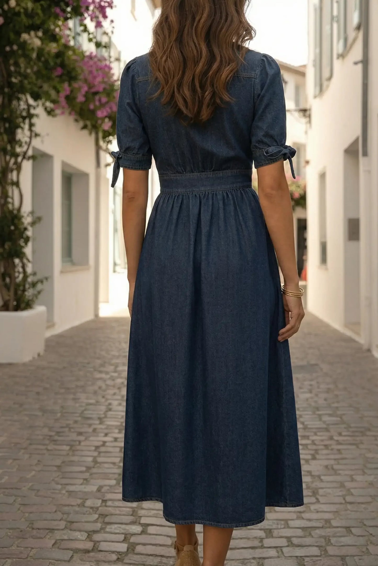 Mujer con vestido largo vaquero azul oscuro, en calle adoquinada, estilo casual elegante.