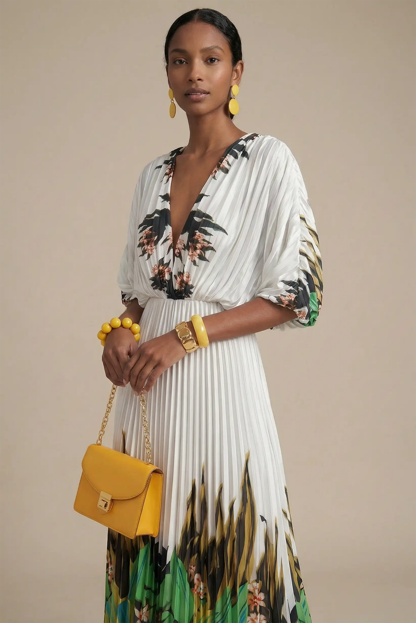 Mujer con vestido blanco plisado estampado tropical verde y accesorios amarillos elegantes