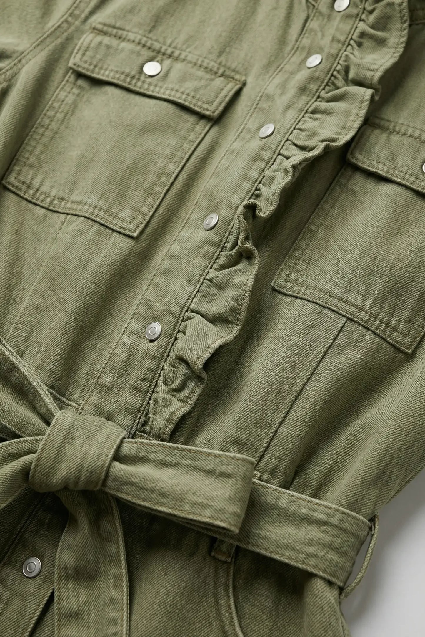 Detalle de vestido corto verde de mezclilla con bolsillos, botones y cinturón para mujer