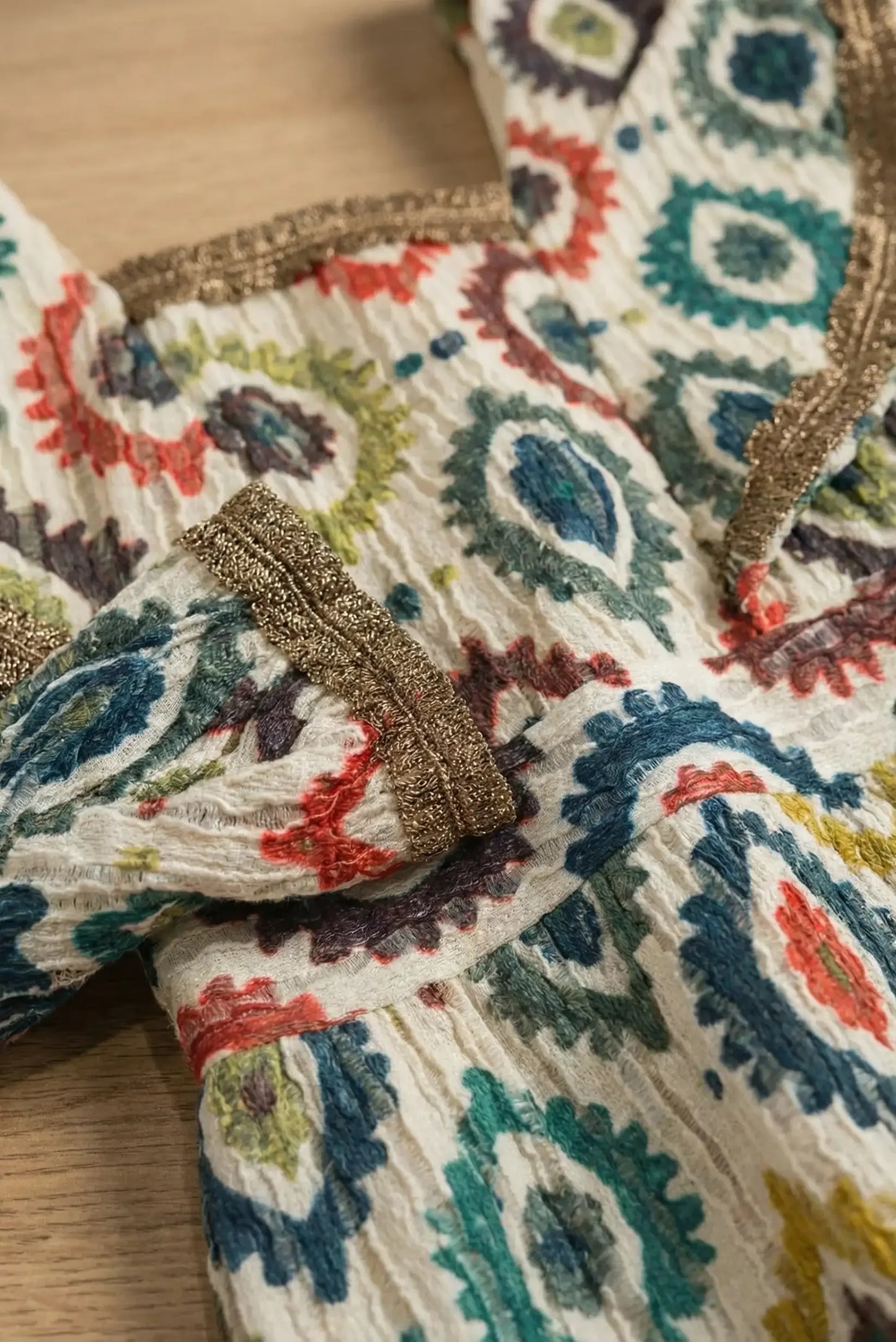Detalle de vestido mujer multicolor con estampado étnico y ribetes dorados en tela texturizada