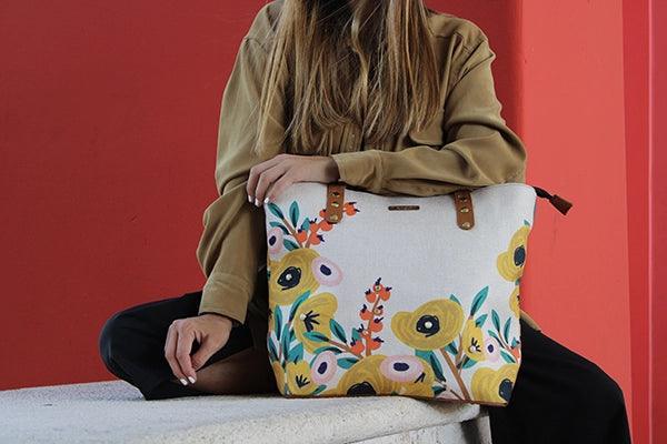 Mujer sentada con bolso de mano grande estampado floral, fondo rojo moderno