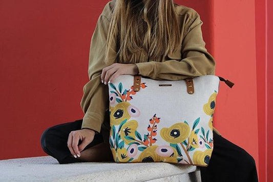 Mujer sentada con bolso de mano grande estampado floral, fondo rojo moderno
