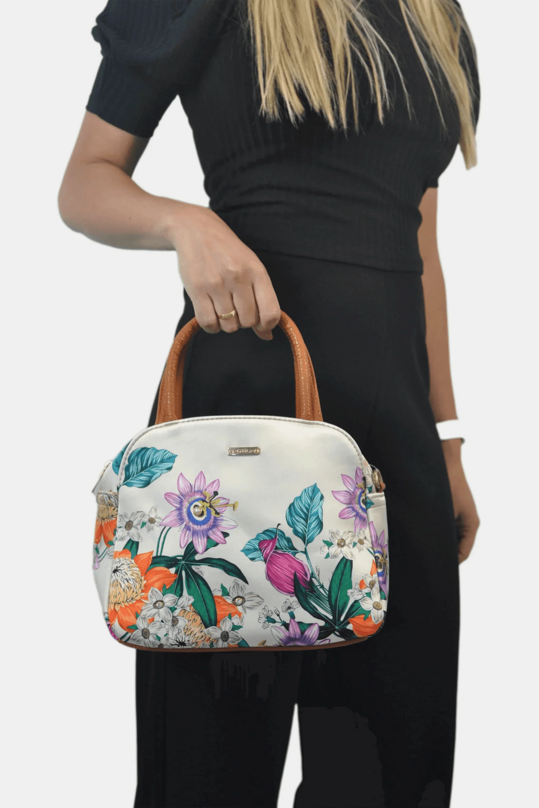 Bolso de mano mediano con estampado floral colorido, asas marrones, mujer de negro