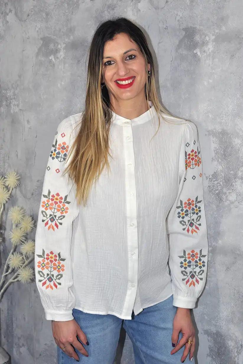 Mujer con camisa blanca de cuello mao y mangas bordadas florales, moda primavera 2025