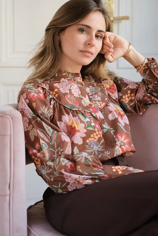 Mujer sentada con camisa marrón de manga larga estampada con flores otoñales elegantes
