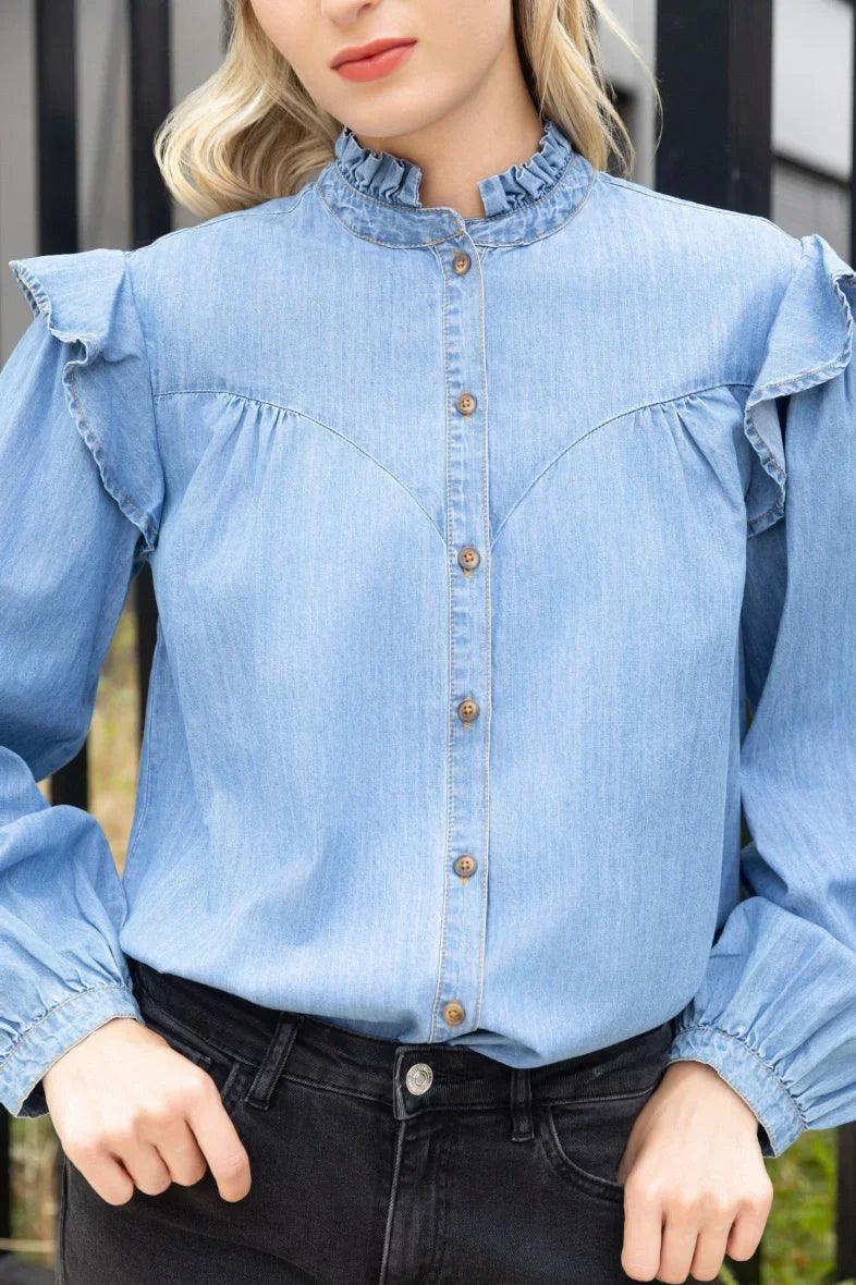 Mujer con camisa vaquera de mezclilla azul con volantes y botones, estilo casual.