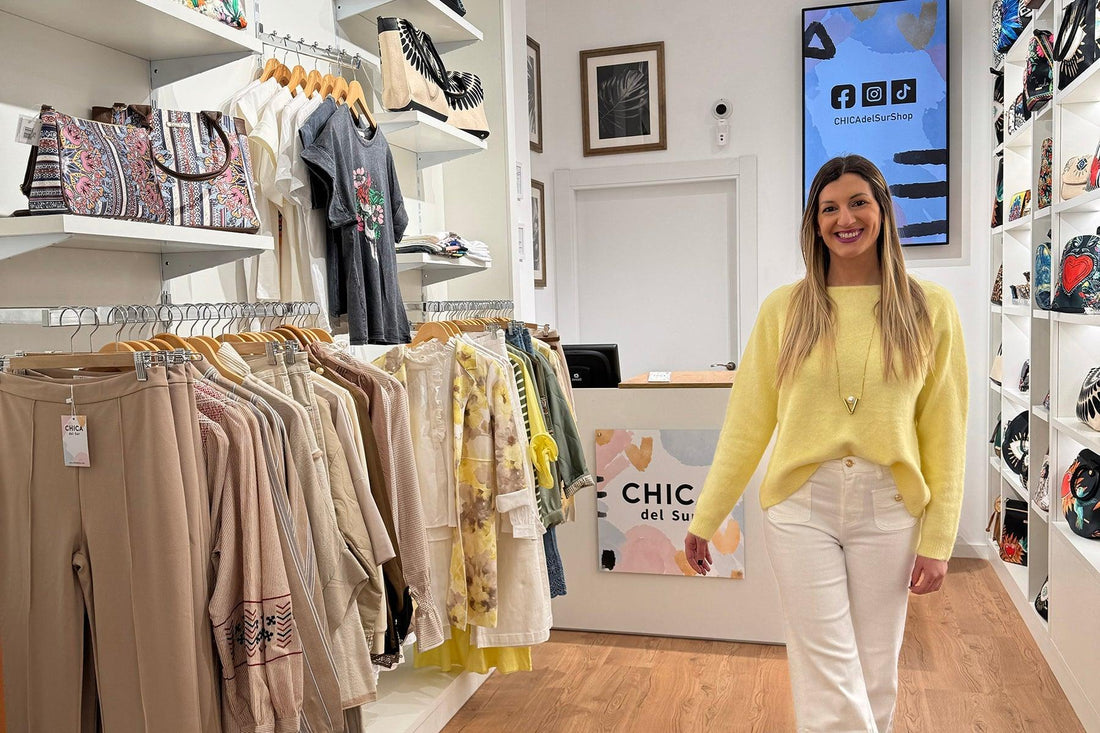 Mujer sonriente en tienda de ropa Chica del Sur, rodeada de moda y accesorios coloridos.