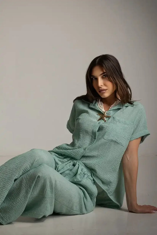 Mujer con conjunto verde agua marina, camisa y pantalón, posando en estudio minimalista