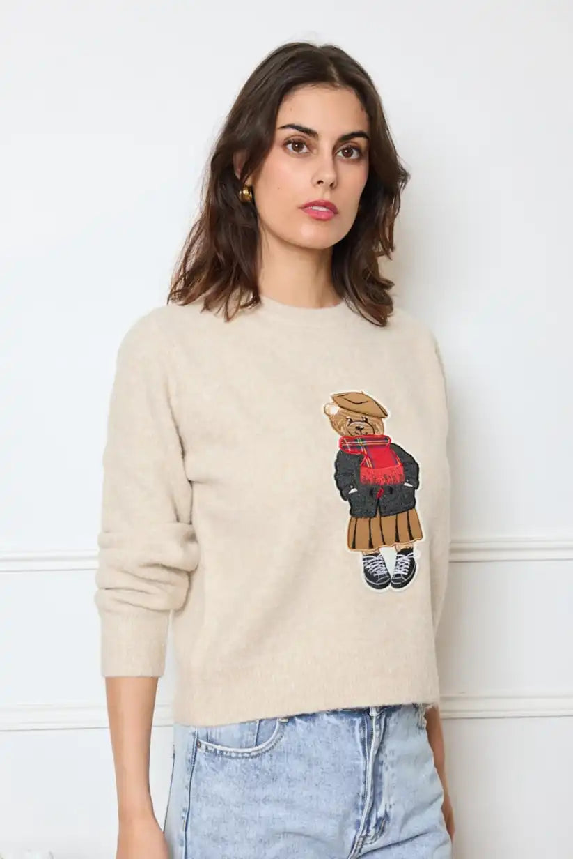 Mujer con jersey beige de otoño con dibujo de oso de peluche, jeans claros