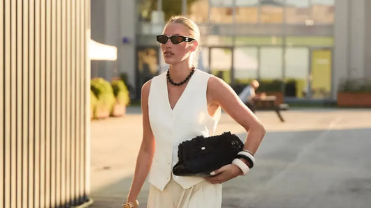 Mujer con conjunto blanco moderno, gafas de sol y bolso negro, moda urbana elegante