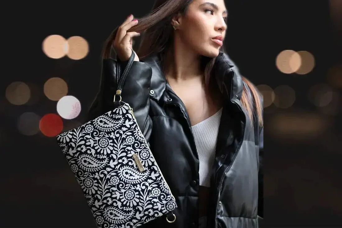 Mujer con bolso negro estampado, chaqueta acolchada y fondo nocturno desenfocado.