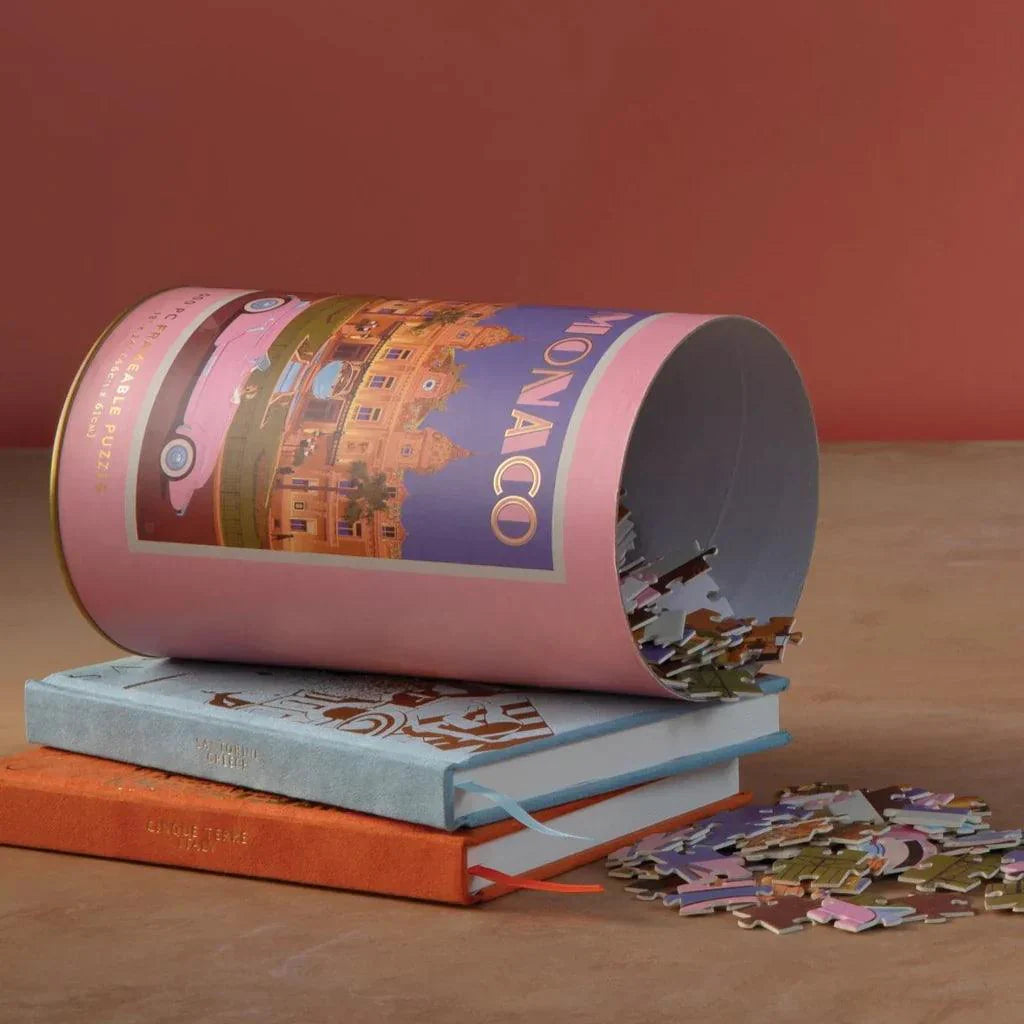 Puzzle de Mónaco en tubo rosa sobre libros, piezas esparcidas, regalo original mujer