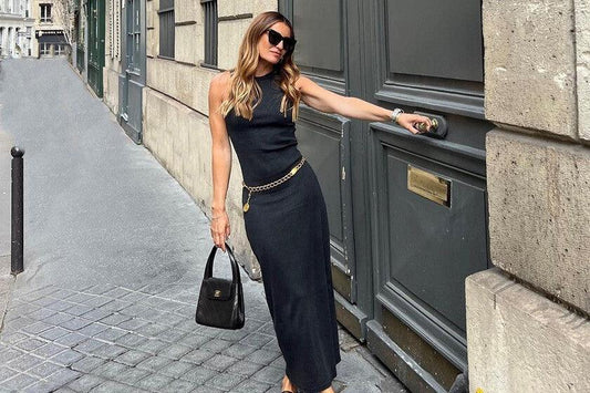 Mujer con vestido negro elegante y bolso en calle urbana, moda para cena en Burgos