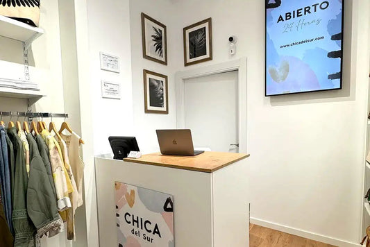 Tienda de moda casual para mujer en España, mostrador moderno, ropa en perchas y letrero digital