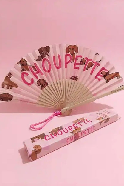 Abanico plegable con perros y texto 'CHOUPEETTE', ideal como complemento de moda femenina en tonos rosas.