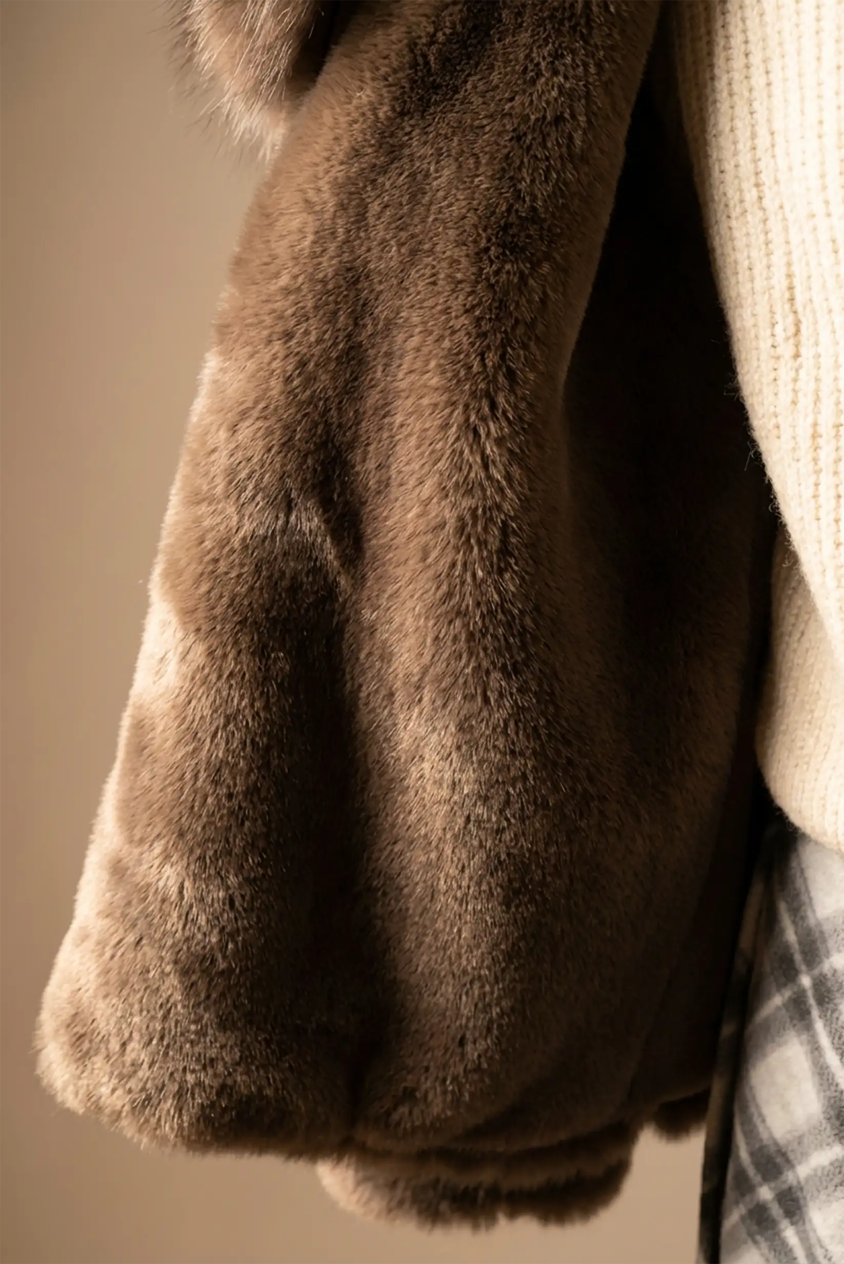 Abrigo de mujer marrón chocolate con pelo sintético y manga abullonada junto a suéter blanco y falda cuadros