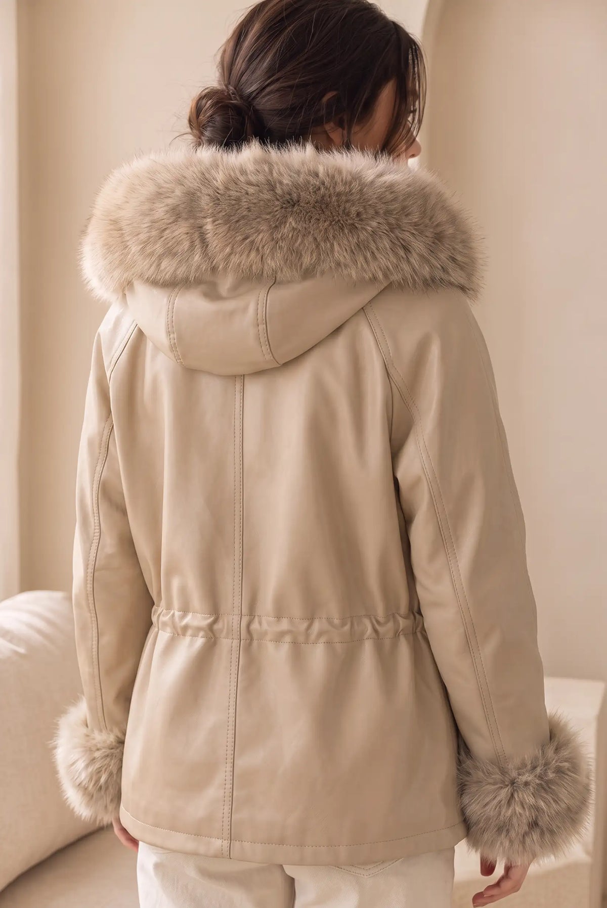 Vista trasera de chaqueta de mujer efecto piel beige con capucha y puños de pelo sintético