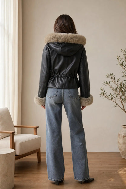 Vista trasera de mujer con chaqueta efecto piel negra y pelo beige de CHICA del Sur y vaqueros.