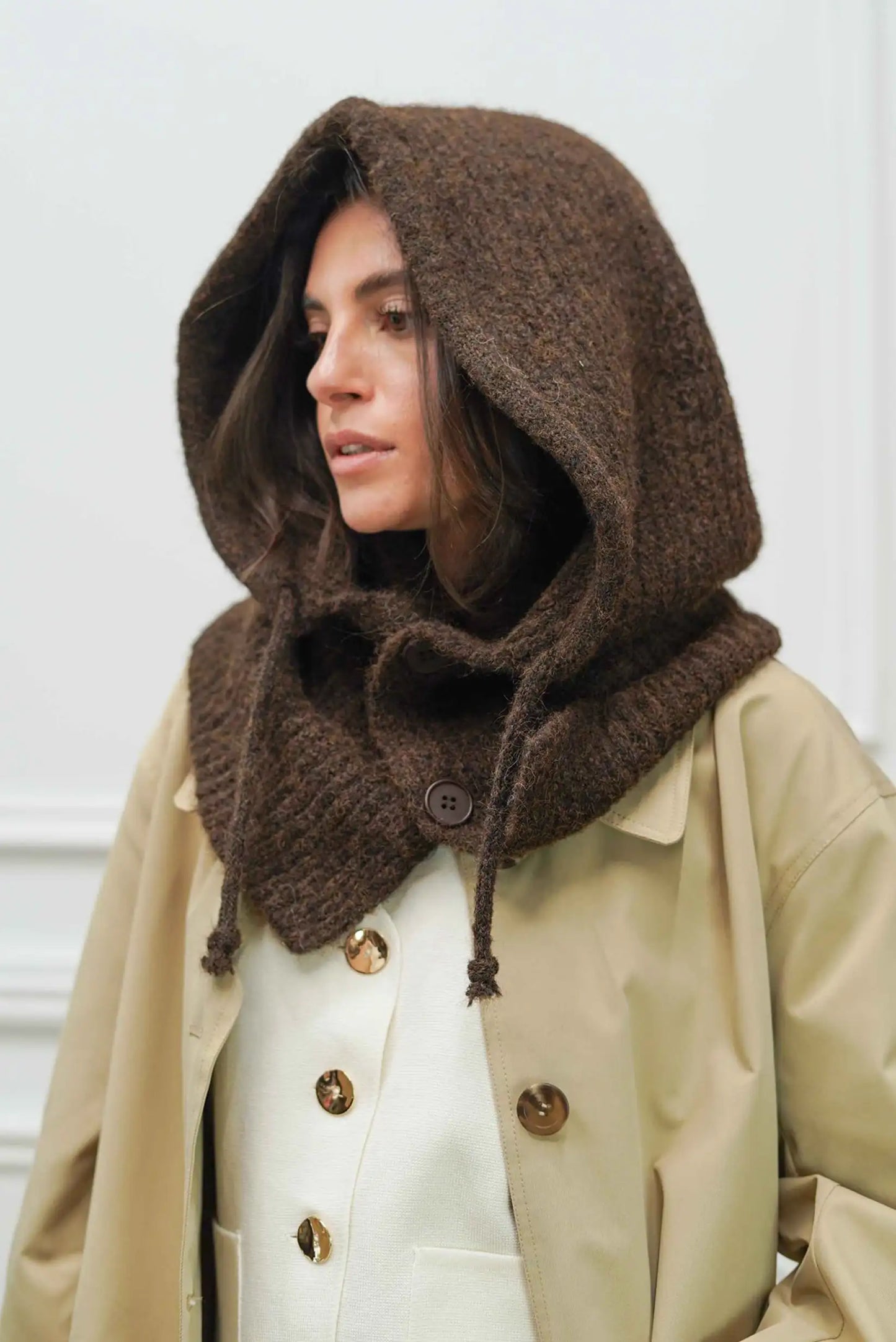 Mujer con pasamontañas marrón chocolate de punto y abrigo beige con botones dorados