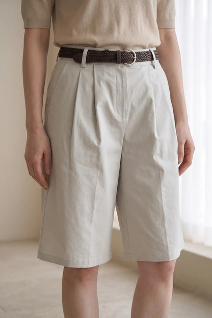 Mujer vistiendo bermudas beige de pinzas con cinturón marrón trenzado