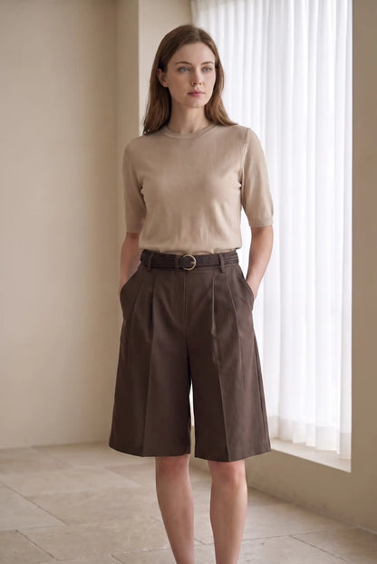 Mujer con camiseta beige de manga corta y bermudas marrones de talle alto con cinturón.