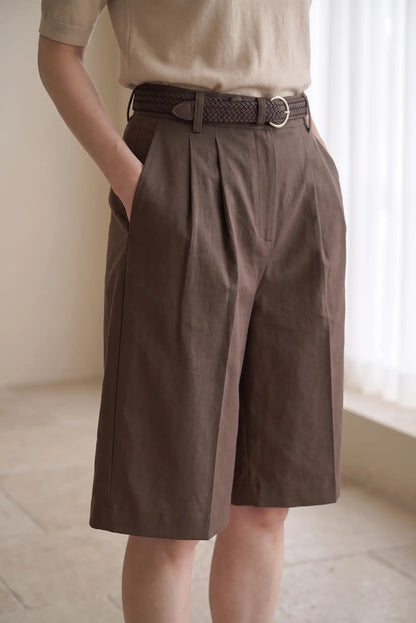 Mujer vistiendo bermudas marrones de talle alto con pinzas y cinturón trenzado