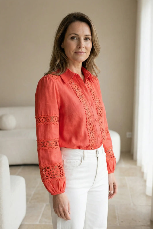 Mujer con blusa coral de manga larga y encaje, moda femenina primavera, pantalón blanco.